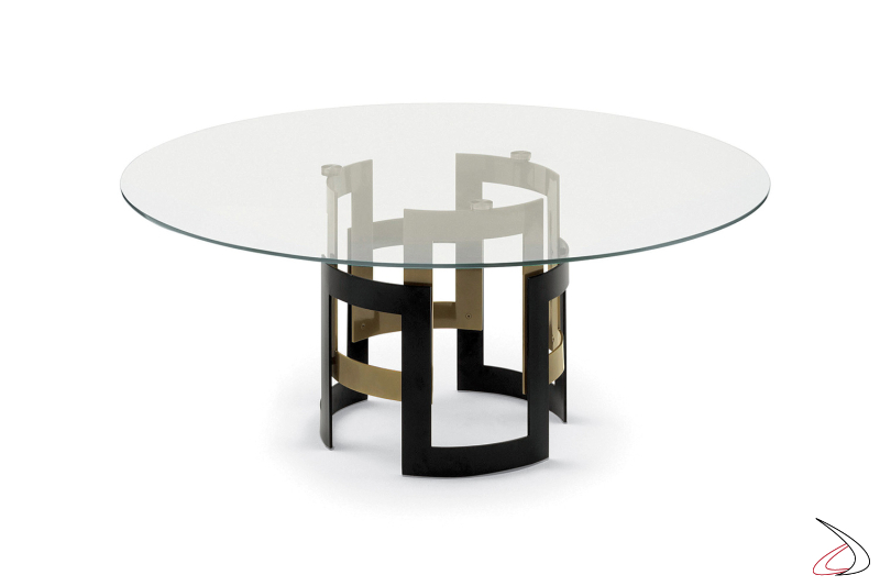 Tavolo rotondo di design con piano in cristallo trasparente e basamento composto da due bracciali bicolori rotondi