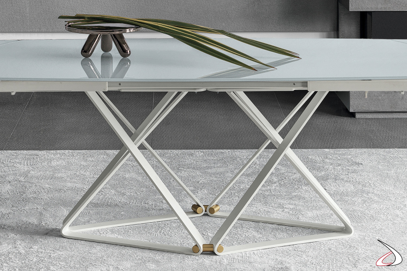 Tavolo di design allungabile con piano a botte in cristallo e basamento a rombo in acciaio verniciato