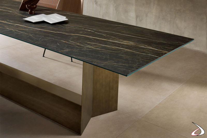 Tavolo moderno e di design caratterizzato da una particolare struttura di metallo e un piano in ceramica stratificato.