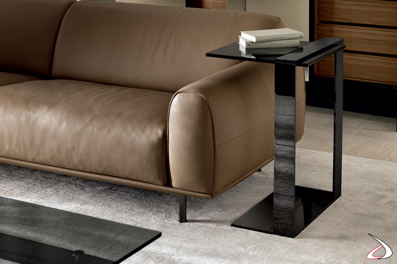 Tavolino fianco divano elegante e dal design minimalista, caratterizzato da una struttura in metallo che sostiene un top in vetro.