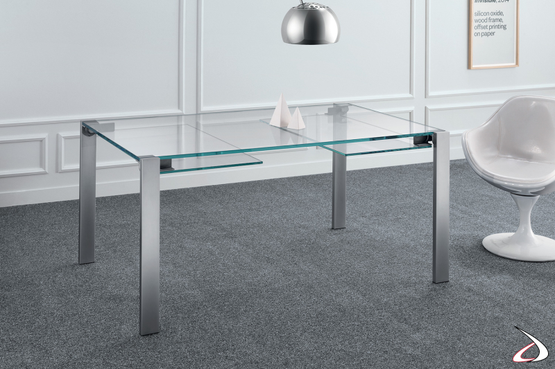 Tavolo moderno e minimalista, caratterizzato da un semplice top in vetro allungabile e gambe in metallo cromato opaco.