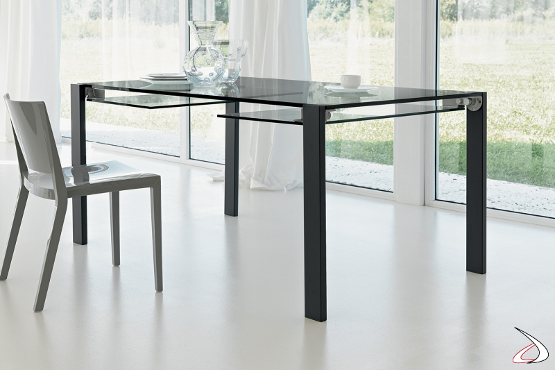 Tavolo moderno dal design minimalista e versatile, con top allungabile i vetro fumè e gambe in metallo verniciato nero.