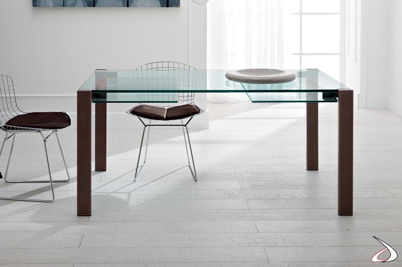 Tavolo elegante dal design minimalista con top in vetro e gambe in cuoio naturale.
