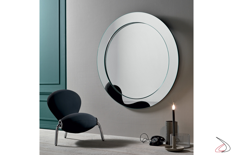 Particolare specchio rotondo a parete, che grazie alla sua cornice leggermente inclinata da profondità e luce all'ambiente.