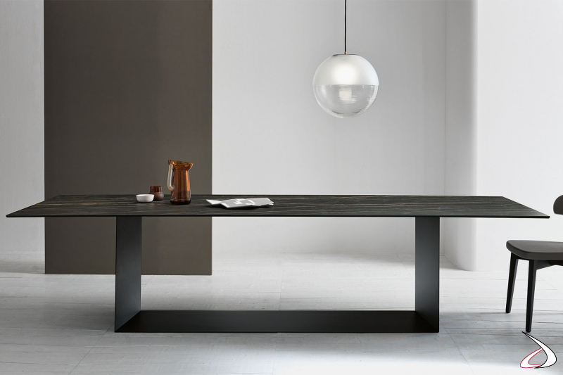 Moderno tavolo di design con struttura centrale in metallo nero e top in ceramica.