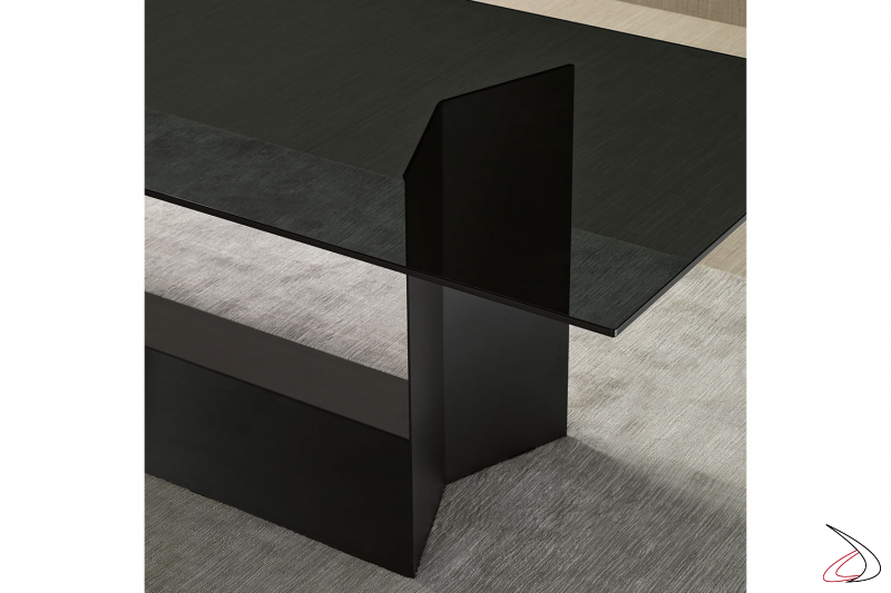 Tavolo moderno e di design con top in vetro fumè e struttura in metallo verniciato nero opaco.