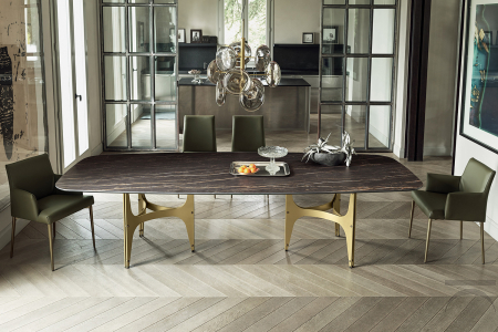 Tavolo lungo di design con piano a botte in supermarmo e doppio basamento in acciaio color oro