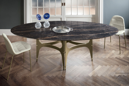 Tavolo ovale di design con piano in supermarmo e basamento centrale ad archi in color oro