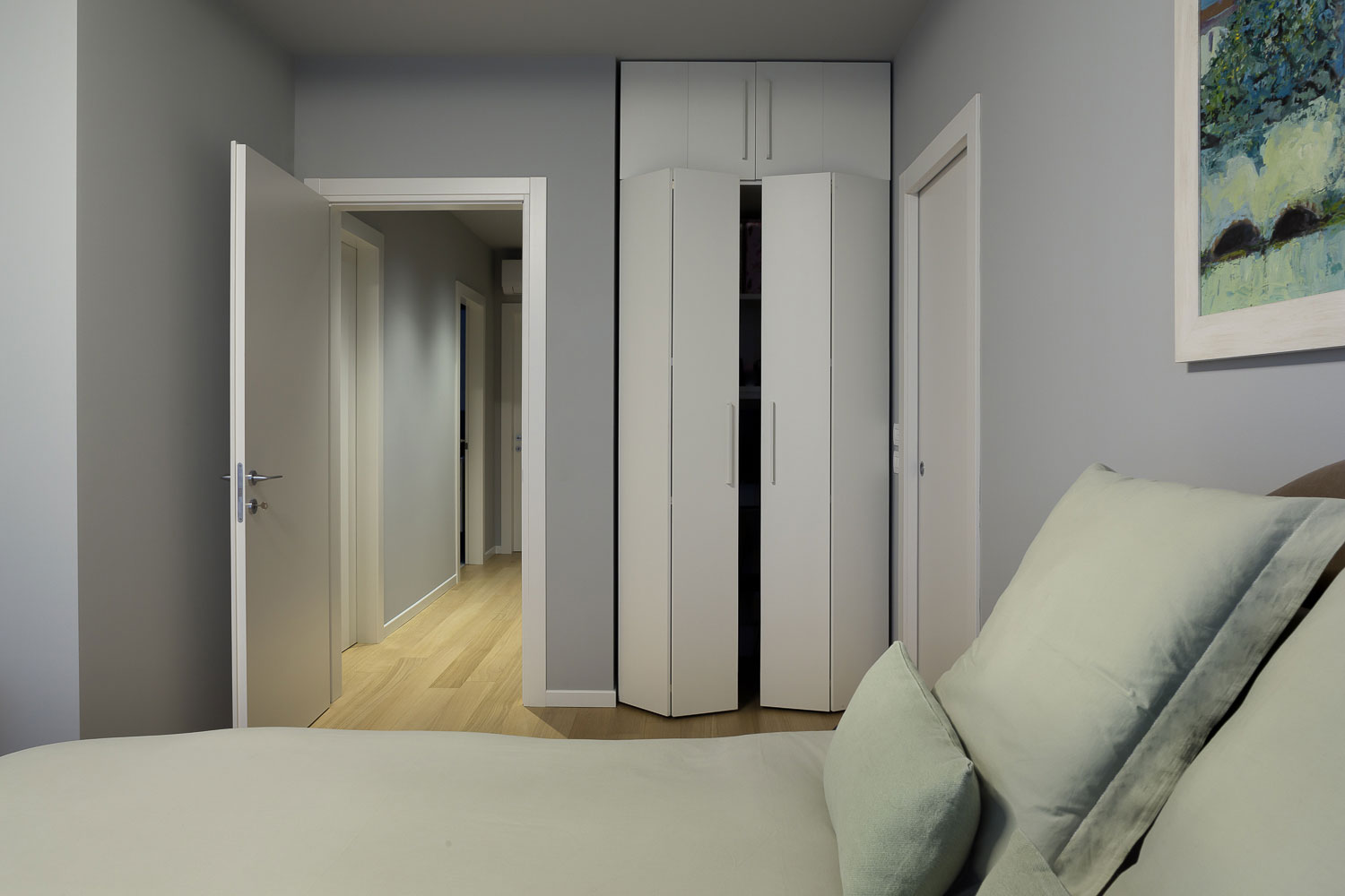 Camera matrimoniale con colori soft e home office a scomparsa